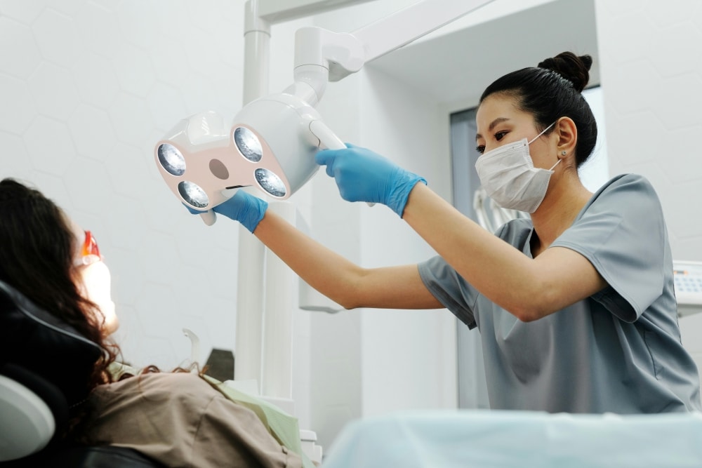 A dentist is adjusting the dental lighting for the patient