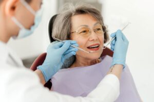 an elderly woman having her teeth examined by the dentist